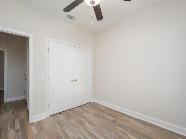 unfurnished bedroom featuring a closet, light hardwood / wood-style flooring, and ceiling fan