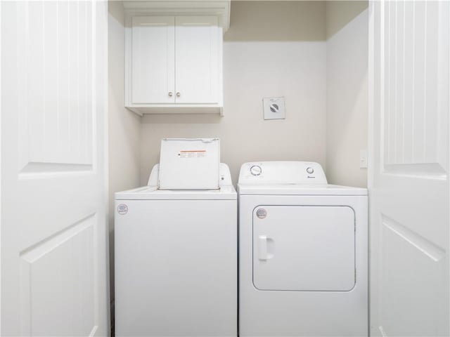 clothes washing area with cabinets and washing machine and dryer