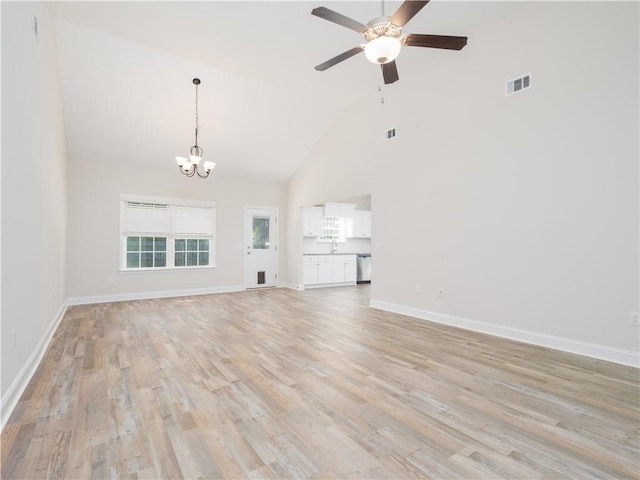 unfurnished living room with ceiling fan with notable chandelier, light wood-type flooring, and high vaulted ceiling