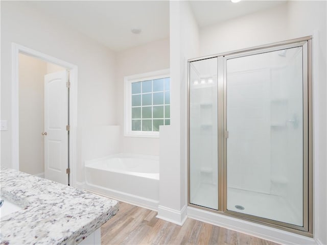 bathroom featuring wood-type flooring and shower with separate bathtub