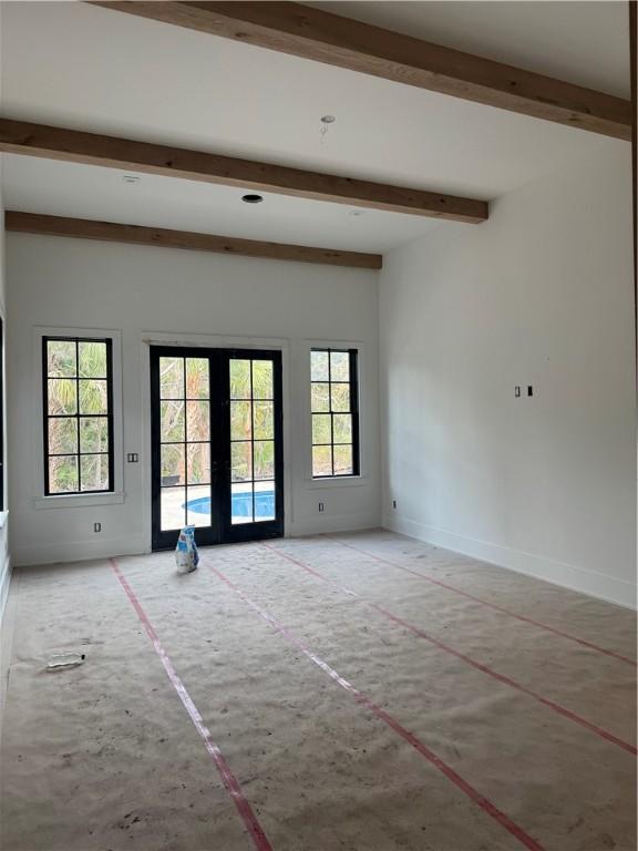 unfurnished room featuring french doors, beam ceiling, and baseboards