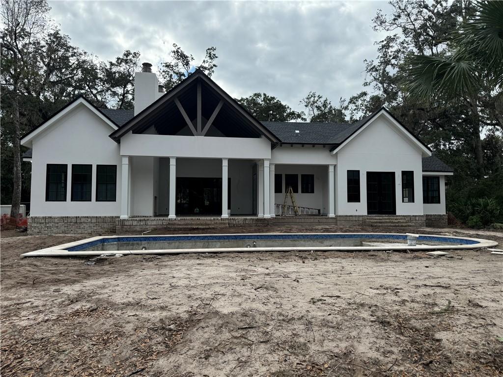 rear view of property with a patio area and an empty pool