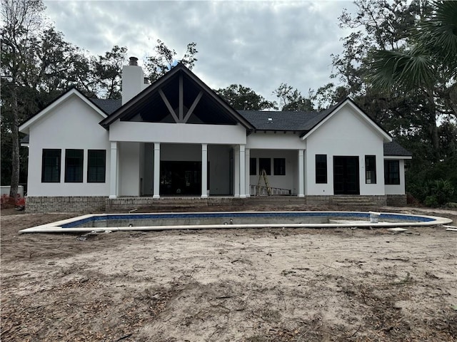 rear view of property with a patio area and an empty pool