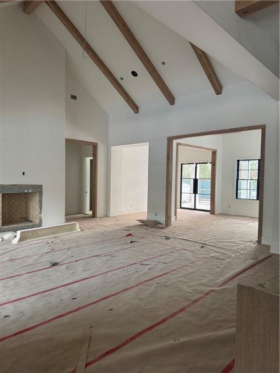 unfurnished living room featuring a fireplace, high vaulted ceiling, and beam ceiling