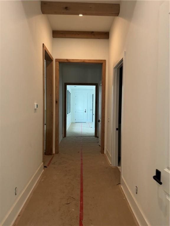 hallway with beam ceiling and baseboards