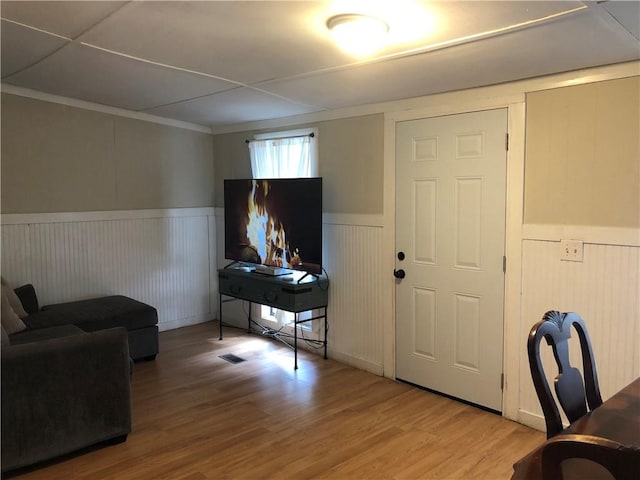 living room featuring wood walls, wood-type flooring, and ornamental molding