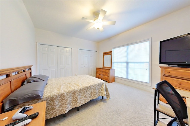 bedroom featuring carpet floors, ceiling fan, and multiple closets