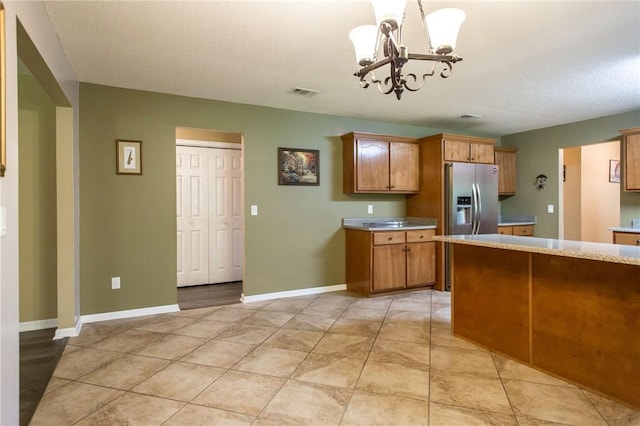 1709 Suwanne Dr, Waycross, GA 31501 - kitchen with stainless steel fridge, a chandelier, light countertops, brown cabinets, and baseboards