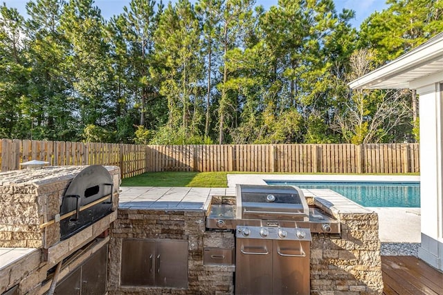 view of patio featuring a fenced in pool, grilling area, and exterior kitchen