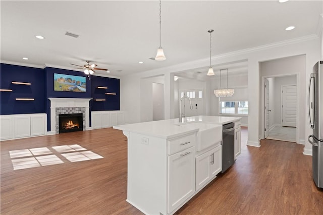 kitchen featuring appliances with stainless steel finishes, sink, a fireplace, white cabinetry, and an island with sink