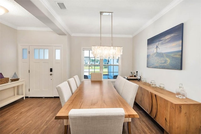 dining room featuring dark hardwood / wood-style floors, an inviting chandelier, and crown molding