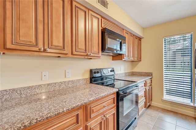 kitchen featuring light countertops, visible vents, light tile patterned flooring, black appliances, and baseboards