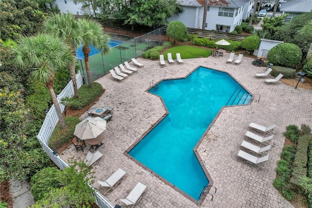 community pool with a patio area and fence