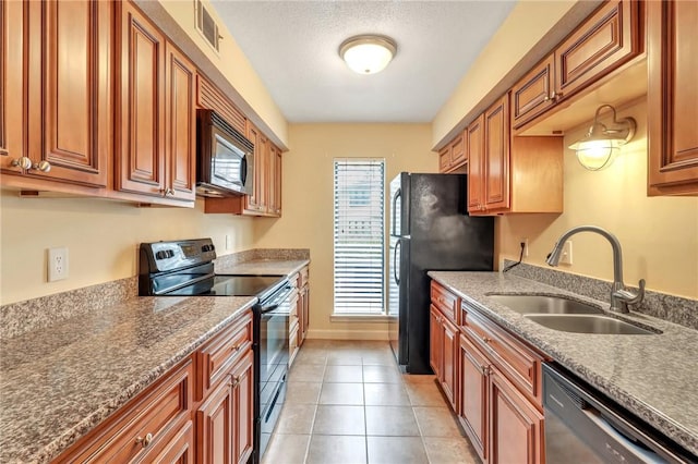 kitchen featuring visible vents, light tile patterned flooring, a sink, black appliances, and baseboards