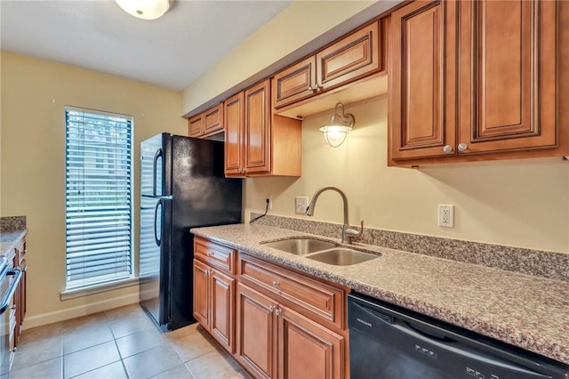 kitchen featuring light tile patterned floors, light countertops, brown cabinetry, a sink, and black appliances