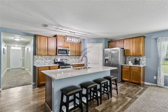 310 Brooklet Cir, Saint Marys, GA 31558 - kitchen featuring stainless steel appliances, a sink, brown cabinetry, a textured ceiling, and tasteful backsplash
