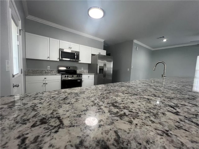 909 E Third St, Darien, GA 31305 - kitchen with appliances with stainless steel finishes, crown molding, light stone countertops, and white cabinets