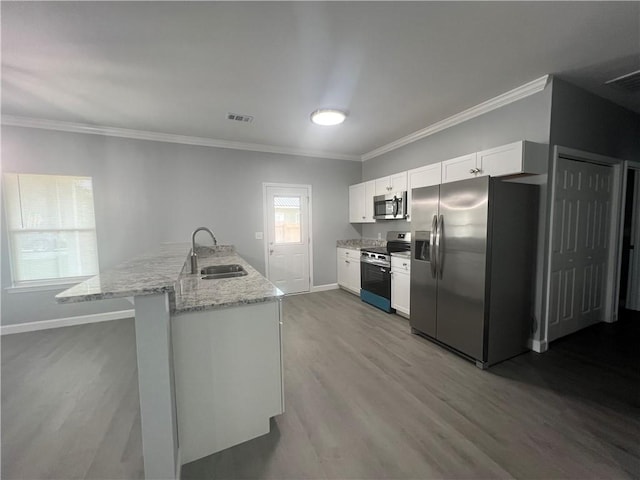 909 E Third St, Darien, GA 31305 - kitchen featuring appliances with stainless steel finishes, wood finished floors, white cabinets, crown molding, and a peninsula
