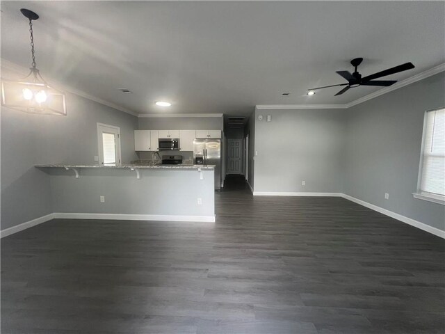 909 E Third St, Darien, GA 31305 - kitchen featuring appliances with stainless steel finishes, ornamental molding, a peninsula, white cabinets, and open floor plan
