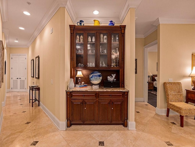 bar featuring crown molding, dark brown cabinets, and light stone countertops