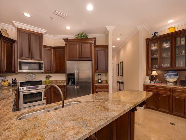 kitchen featuring light stone counters, dark brown cabinetry, stainless steel appliances, and sink