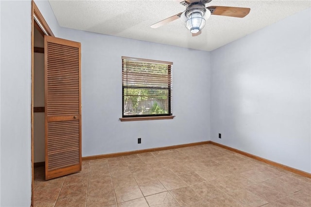 unfurnished bedroom featuring ceiling fan, light tile patterned floors, a textured ceiling, and a closet