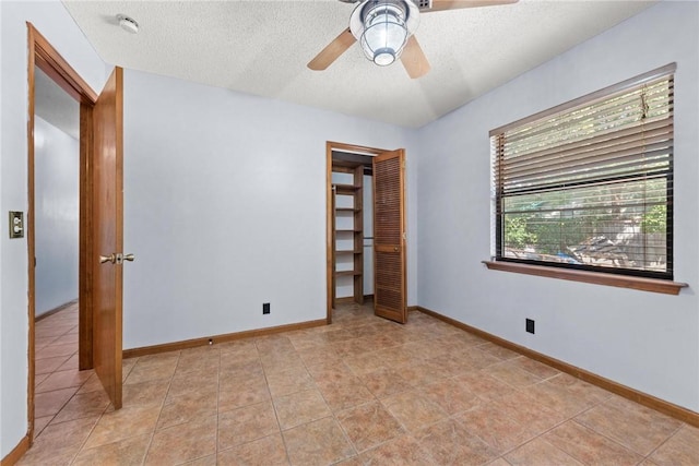 unfurnished bedroom featuring light tile patterned flooring, a textured ceiling, a closet, and ceiling fan