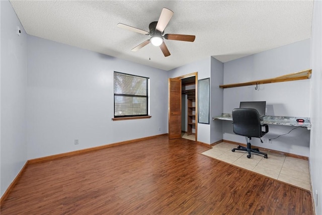 office area with ceiling fan, light hardwood / wood-style flooring, built in desk, and a textured ceiling