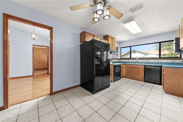 kitchen with ceiling fan, sink, black appliances, light tile patterned floors, and decorative light fixtures