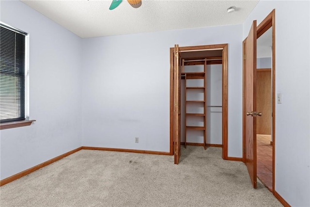 unfurnished bedroom featuring light carpet, a textured ceiling, a closet, and ceiling fan