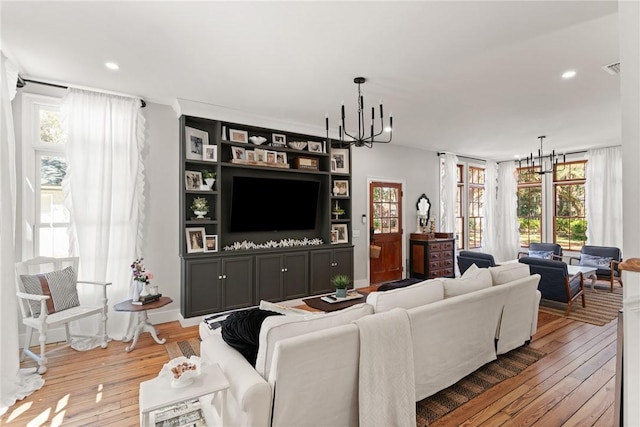 living room with recessed lighting, an inviting chandelier, and light wood-style flooring