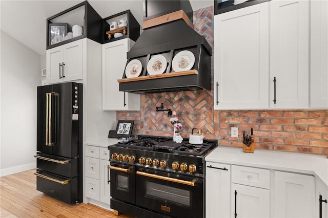 kitchen featuring premium range hood, black appliances, white cabinets, and light countertops