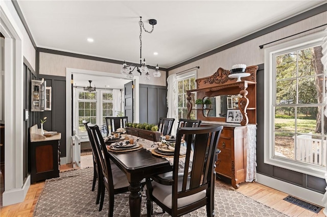 dining area featuring a healthy amount of sunlight, crown molding, and a decorative wall