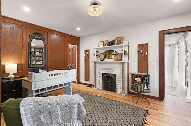 living area featuring light wood finished floors, recessed lighting, a brick fireplace, and baseboards