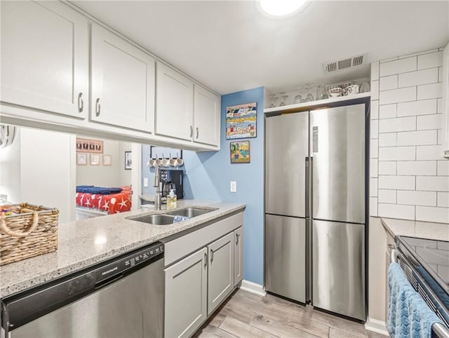 1524 Wood Ave Unit 106, Saint Simons Island, GA 31522 - kitchen featuring visible vents, a sink, light stone counters, stainless steel appliances, and light wood-style flooring