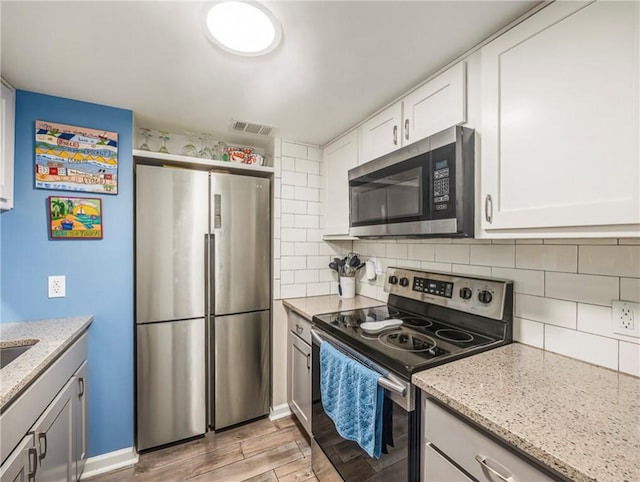 1524 Wood Ave Unit 106, Saint Simons Island, GA 31522 - kitchen featuring white cabinets, light stone countertops, appliances with stainless steel finishes, and light wood-style floors
