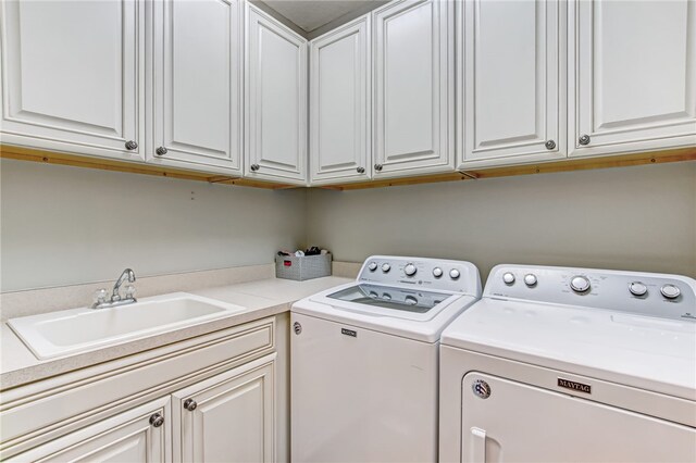 laundry area featuring cabinets, washing machine and clothes dryer, and sink