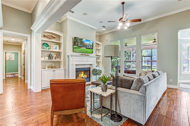 living room featuring crown molding, ceiling fan, and light wood-type flooring