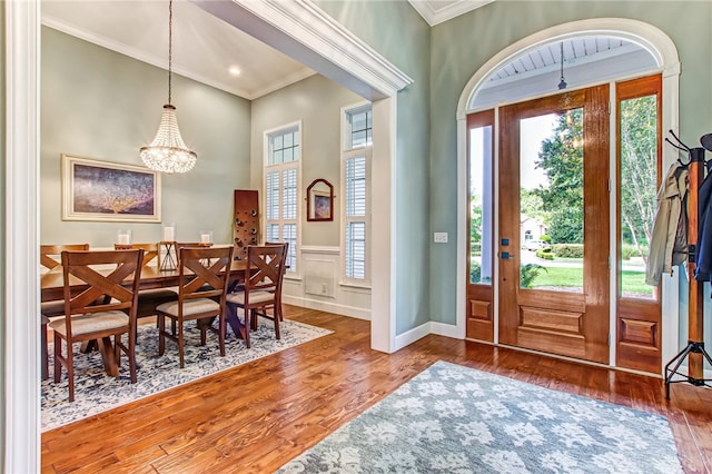 entrance foyer with a chandelier, crown molding, and wood-type flooring