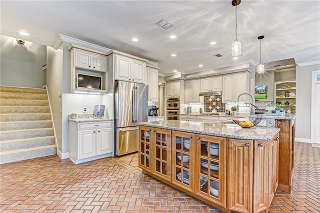 kitchen featuring a center island, hanging light fixtures, stainless steel appliances, light stone counters, and crown molding