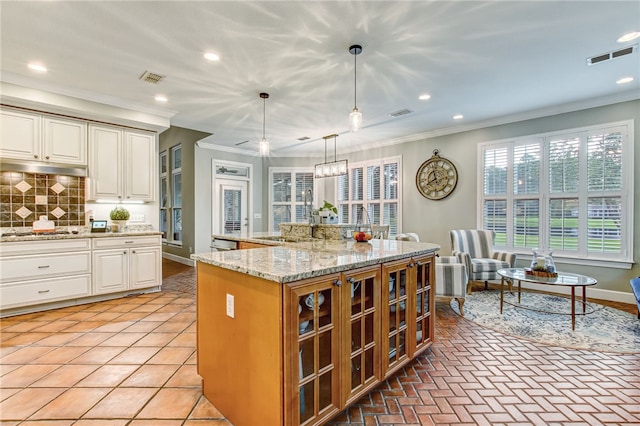 kitchen featuring crown molding, decorative backsplash, appliances with stainless steel finishes, decorative light fixtures, and a kitchen island