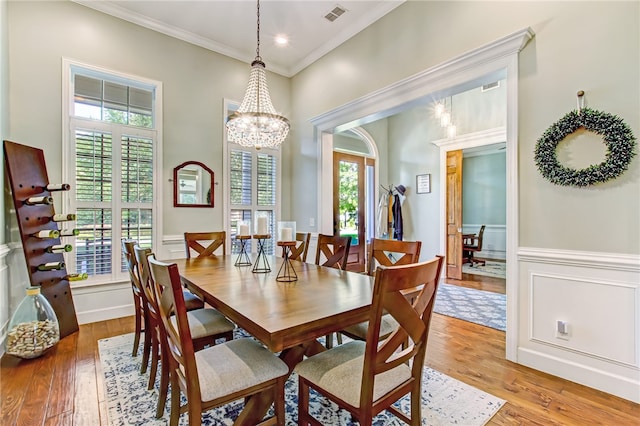 dining area with ornamental molding, light wood-type flooring, and a healthy amount of sunlight