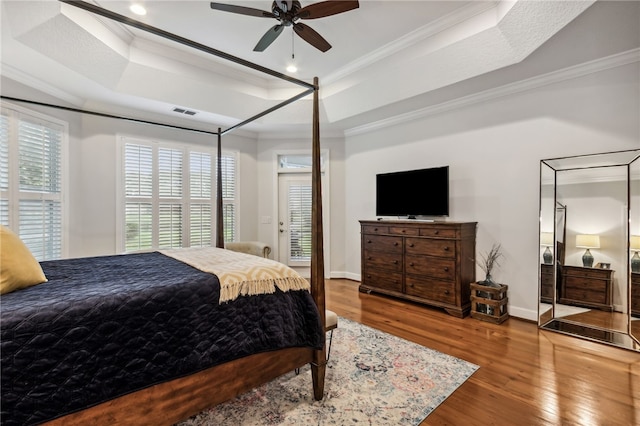 bedroom with a raised ceiling, ceiling fan, wood-type flooring, and ornamental molding