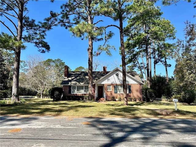 view of front of home with a chimney, a front lawn, and brick siding