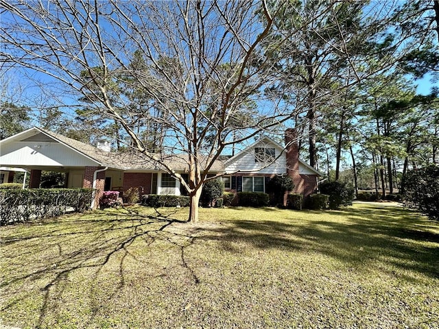 view of front of home featuring a front yard, a chimney, and brick siding