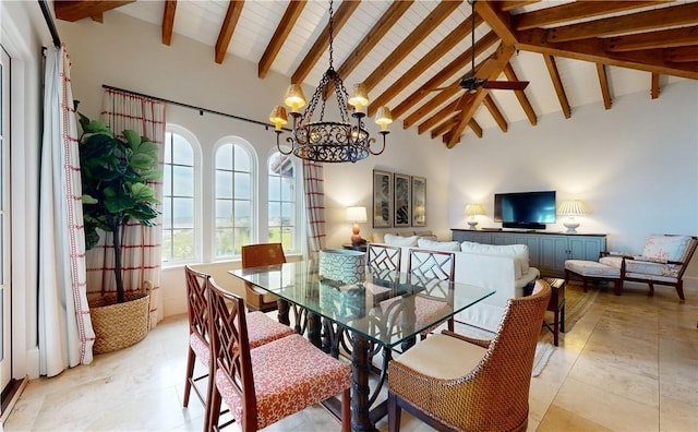 dining space with beamed ceiling, ceiling fan with notable chandelier, and high vaulted ceiling