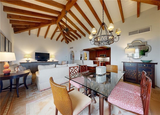 dining area featuring ceiling fan with notable chandelier, beam ceiling, and high vaulted ceiling