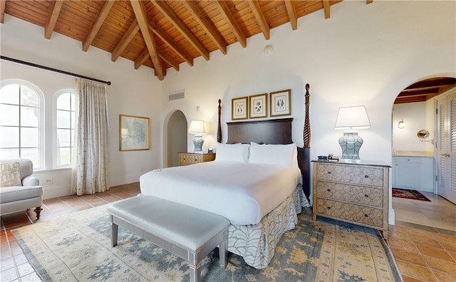 bedroom with beam ceiling, ensuite bath, high vaulted ceiling, and wooden ceiling