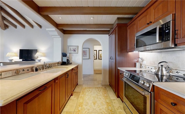 kitchen with sink, light tile patterned floors, tasteful backsplash, beamed ceiling, and stainless steel appliances