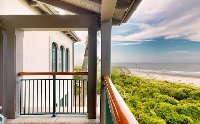 balcony with a water view and a view of the beach